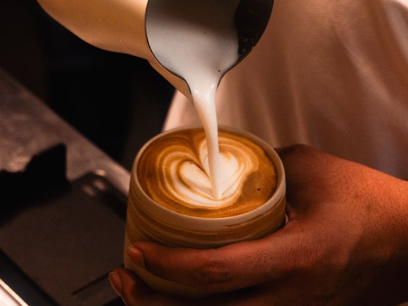 Various coffee drinks including espresso, cappuccino, latte, flat white, mocha, and cold brew displayed on a café table, showcasing different types of coffee.